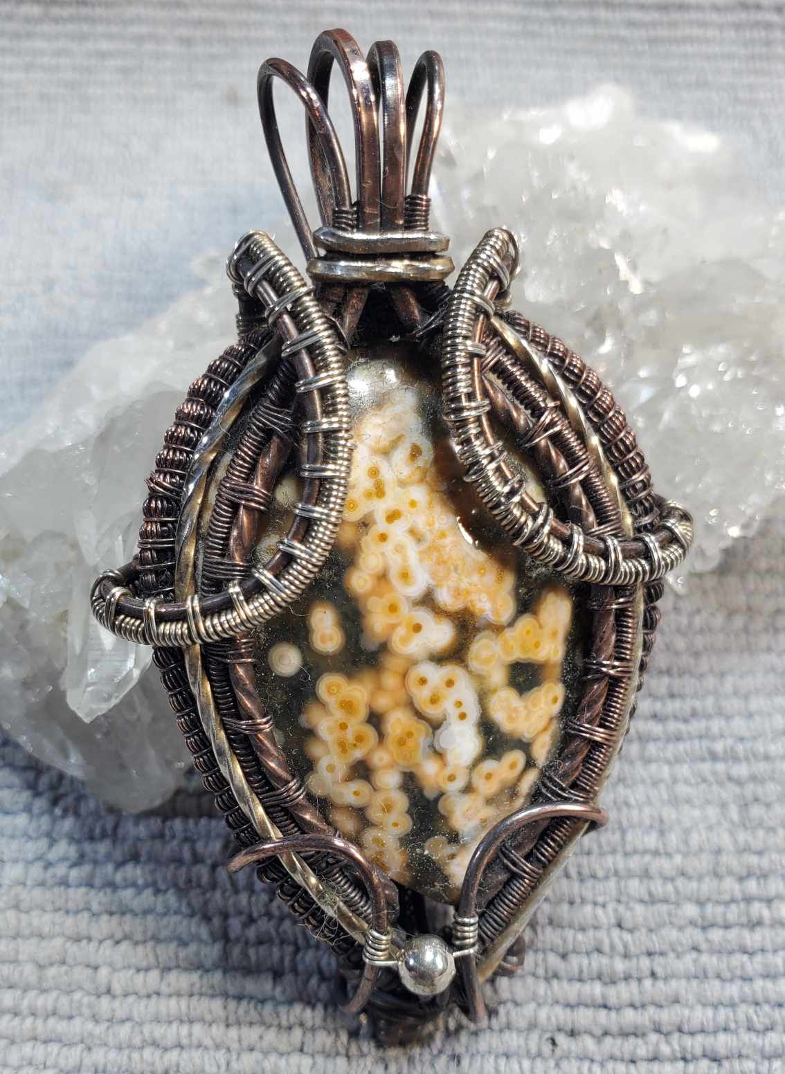 Ocean jasper cabochon with cream and orange orbs, wrapped in a copper and sterling silver wire weave